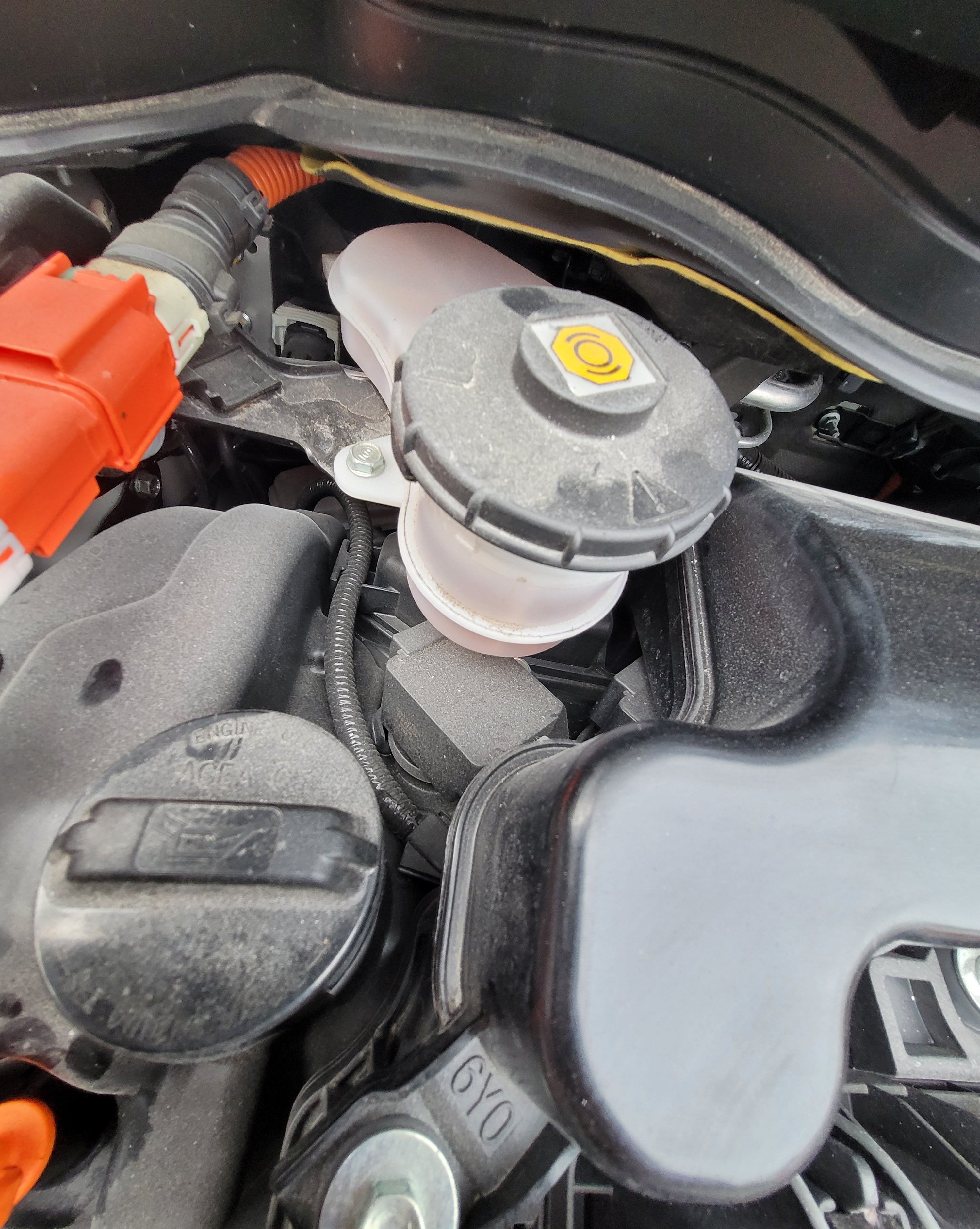 Close-up of car engine components with a focus on the air filter and surrounding parts.