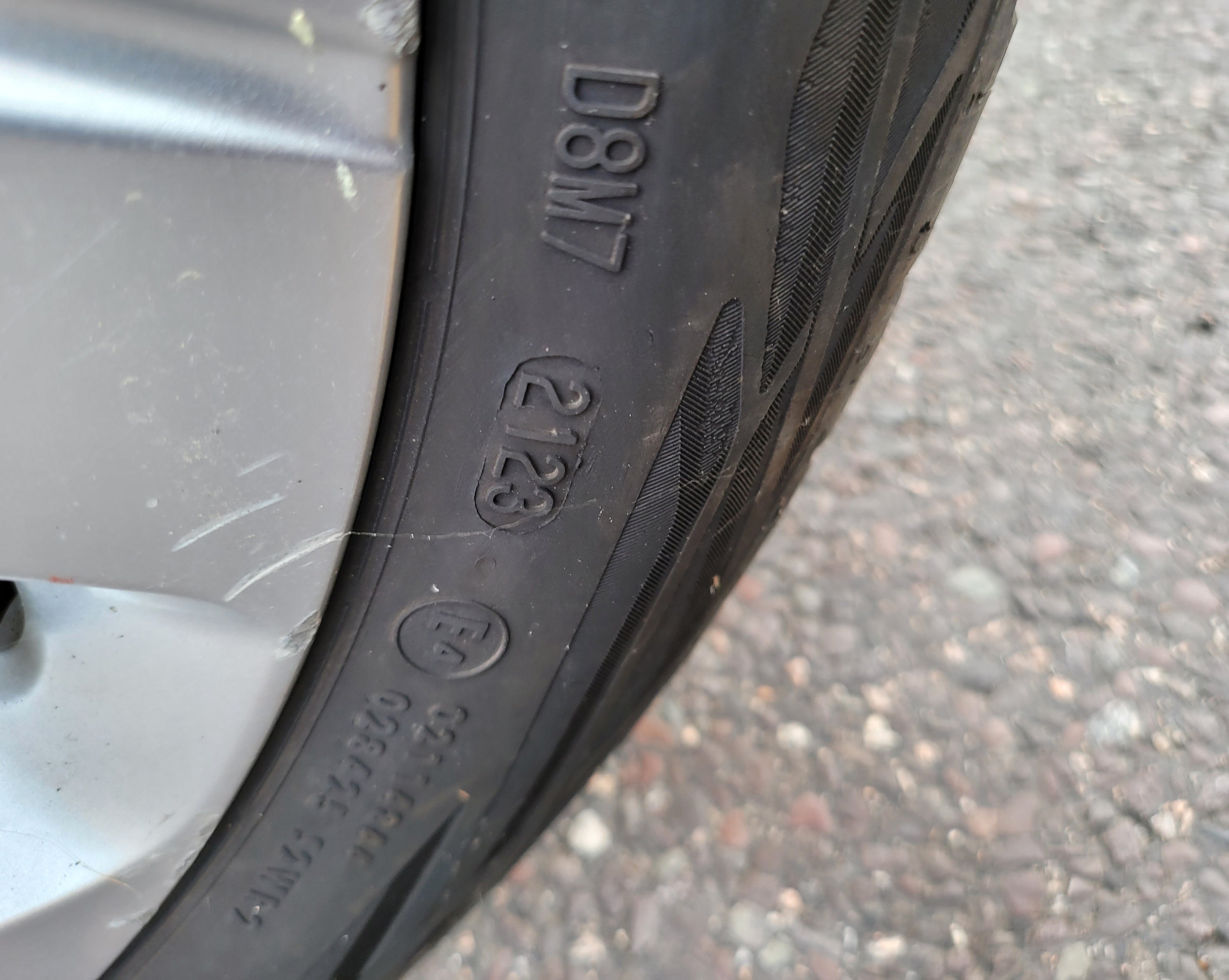 Close-up of a tire with visible tread pattern and text on a road surface