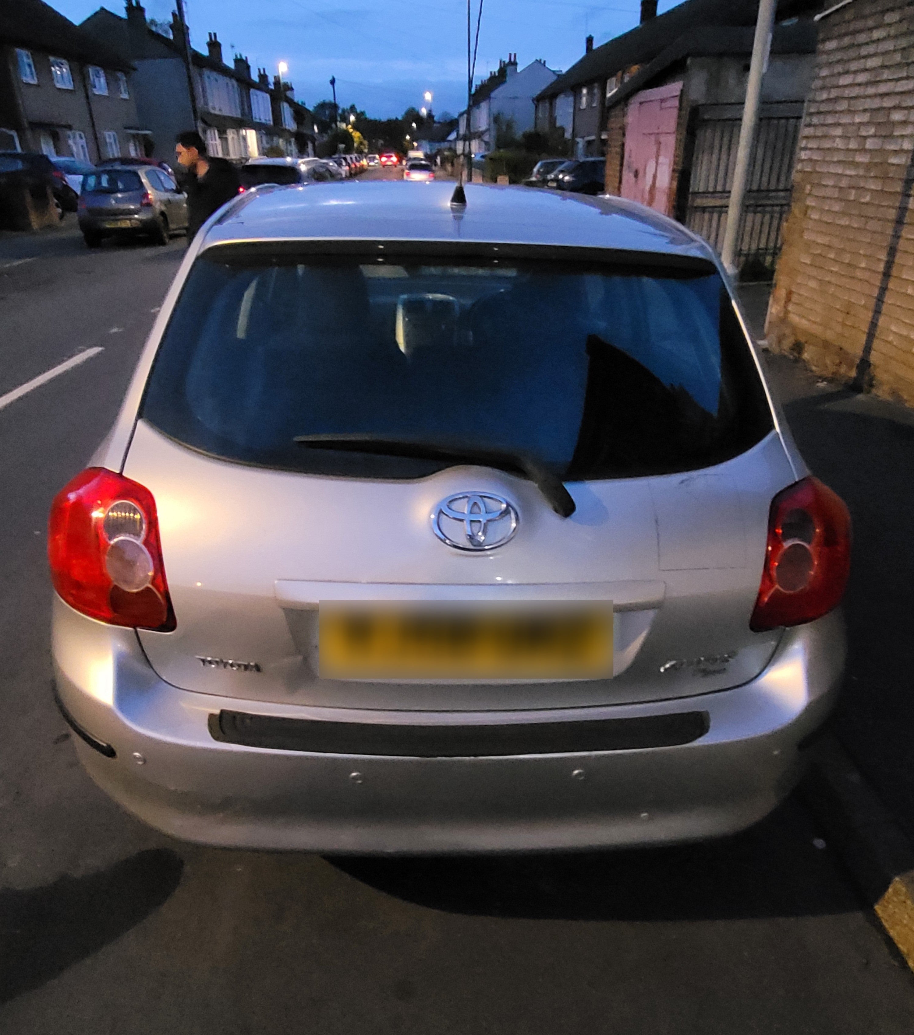Silver Toyota car parked on a residential street at dusk