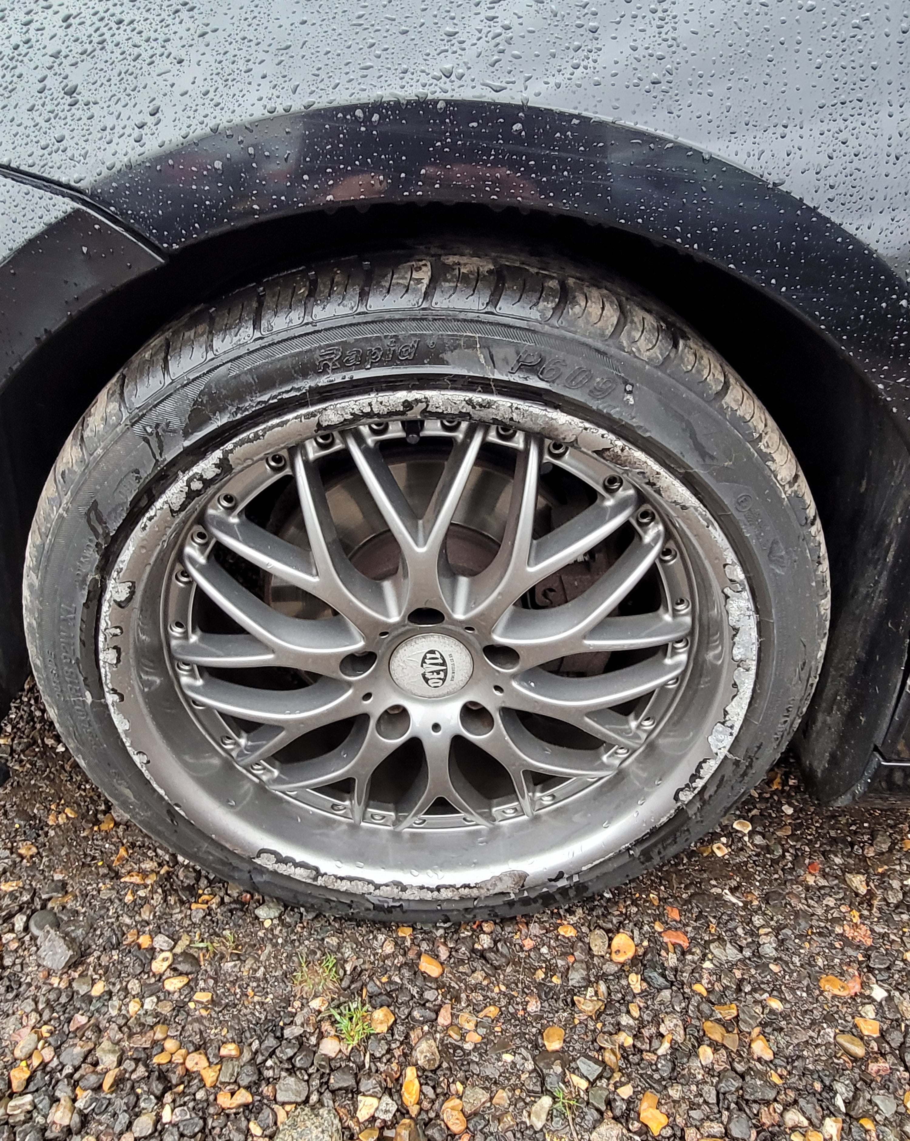 Car tire with a silver alloy wheel on a road surface