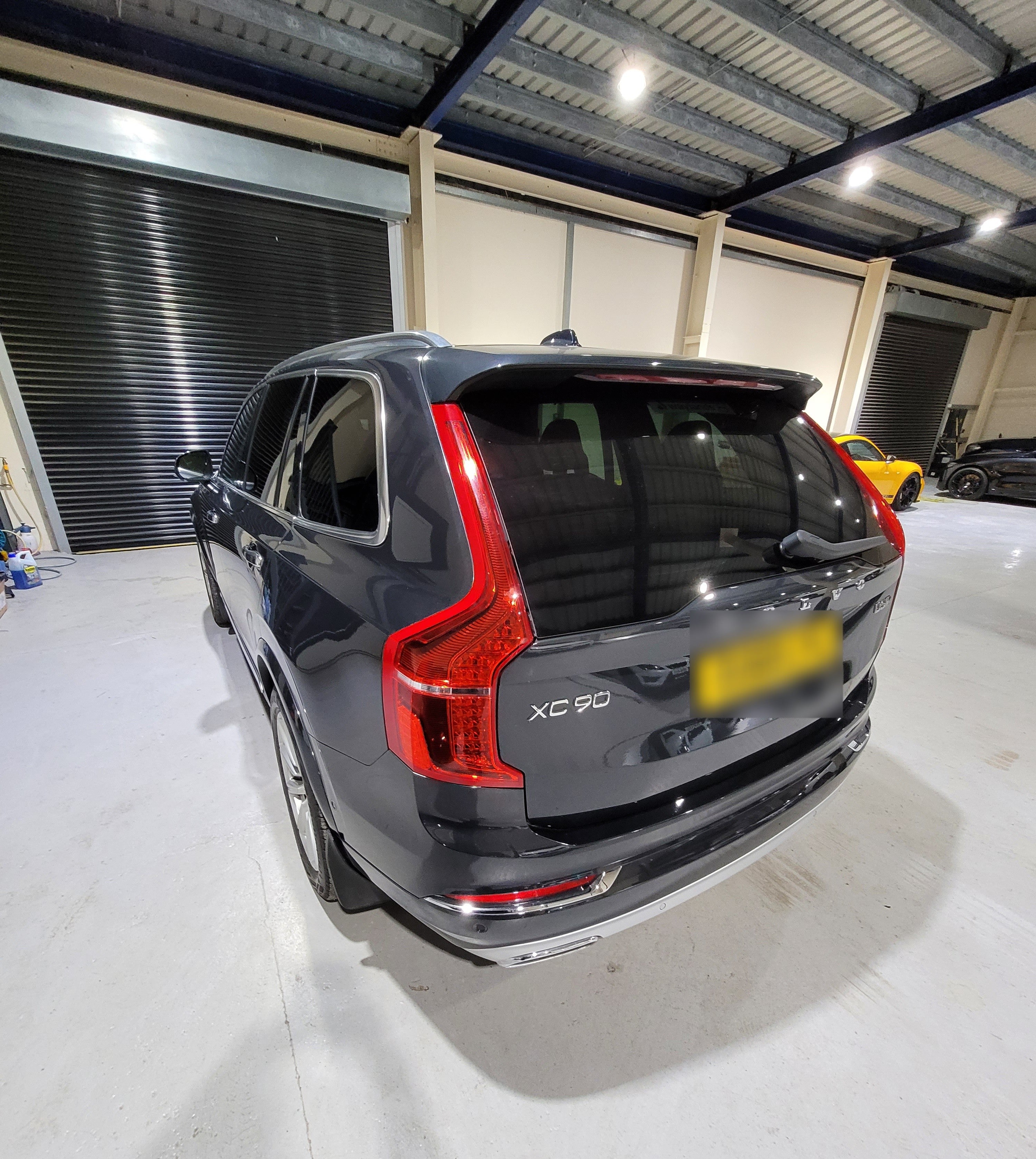 Black Volvo XC90 SUV parked inside a warehouse.